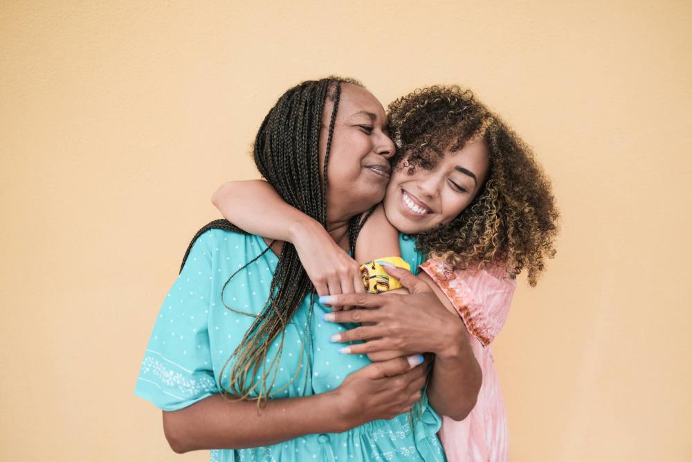 Two Black women are embracing and smiling
